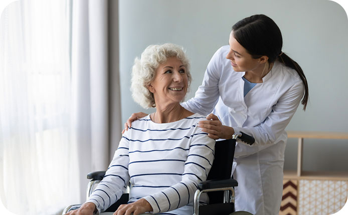 Young woman doctor give help support handicapped old lady patient sitting in wheelchair, female caregiver or nurse assist take care of smiling senior disabled grandma, elderly healthcare concept