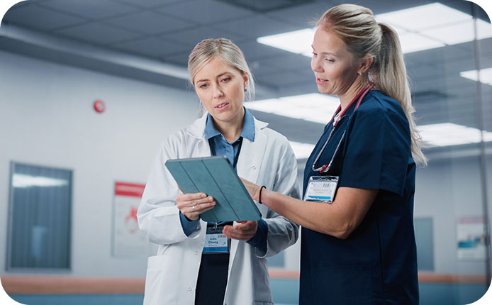 Health Care Medical Hospital. Professional Nurse and Doctor Walking Through Hallway, Talking, Use Digital Tablet Computer, Discuss' Patient Treatment, Drugs or Therapy.